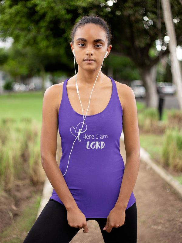 Young woman standing on walking trail wearing a purple racerback tank with cross/heart logo and the words Here I am Lord.