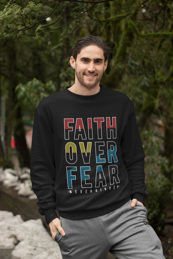 Smiling caucasian man standing with trees in the background and snow on the ground. Wearing a black sweatshirt with the words Faith Over Fear Never Give Up in colorful letters on the front.